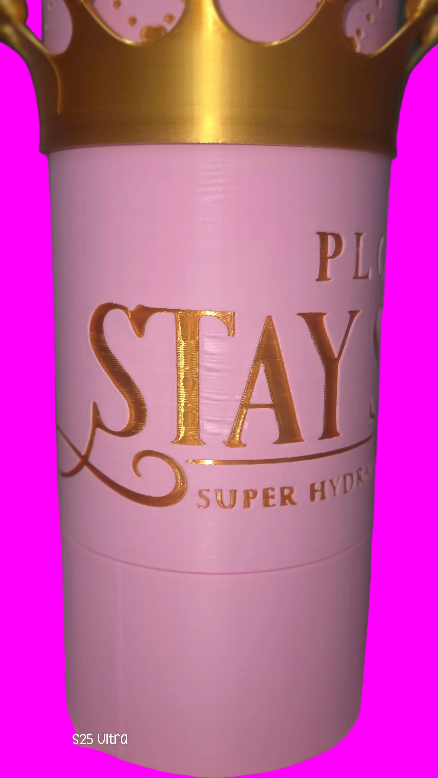 A close-up of a pink cylindrical cosmetic container with a gold crown graphic at the top and gold lettering that reads 'PLC STAY S SUPER HYDR'.